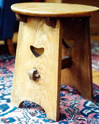 Small oak table by Liberty &  Co with squashed heart piercing, supports to top and pegged stretcher